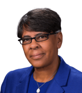 Person wearing glasses and a blue blazer, looking at the camera with a neutral expression.